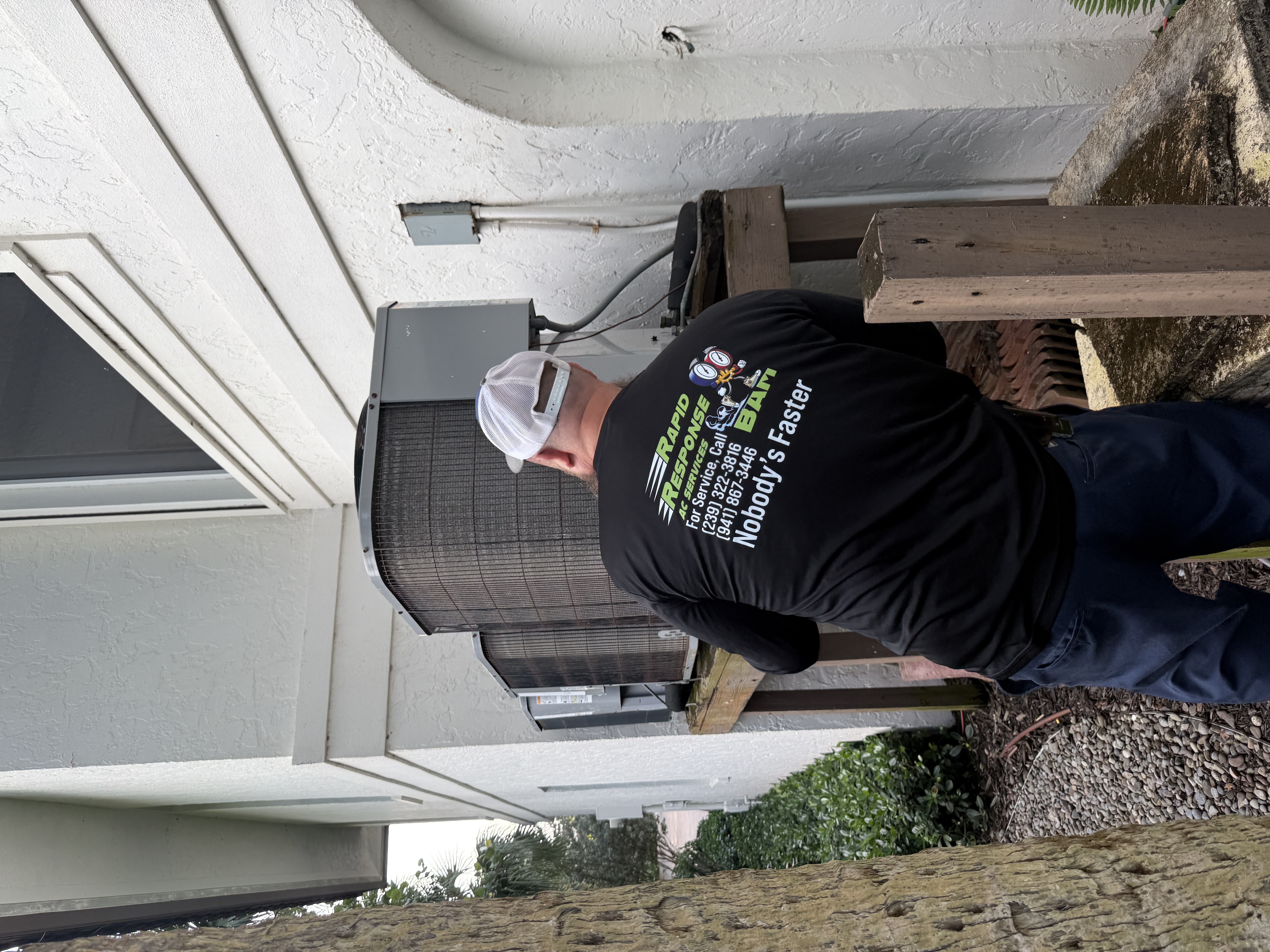Rapid Response AC technician actively working inside a condenser unit at a Fort Myers residential property